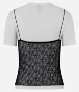 Remera de algodón blanca con encaje negro sobrepuesto estilo camisola. Presenta cuello redondo, mangas cortas y un diseño de doble capa que combina una camiseta básica con un top de encaje.