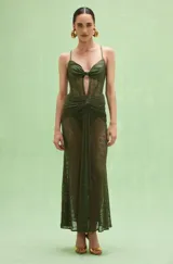 Vestido largo verde militar de diseño translúcido en tejido de encaje con patrón geométrico, escote con nudo frontal, tirantes finos y detalles drapeados en la cintura.