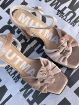 Sandalias de tacón alto Mutma modelo Ñoma, confeccionadas completamente en terciopelo color verde militar. Presentan una plataforma delantera, detalle de doble nudo o moña en la puntera, taco ancho y tira con hebilla ajustable en el tobillo.