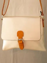 Bandolera negra de cuero sintético con correa larga naranja y cierre con hebilla naranja.