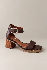 Sandalias de cuero marrón, con punta cuadrada, taco ancho de madera y tira ajustable con hebilla en el tobillo.
