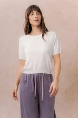 Remera tejida fina de color blanco, con escote redondo, manga corta y terminaciones en rib en cuello, mangas y ruedo. De calce relajado y largo corto.