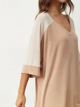 Remera oversize de manga corta con escote en V, de diseño bicolor en tonos beige y tostado, con mangas raglán y corte amplio.