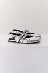 Balerina negra de cuero con punta fina y dos correas marrones con hebilla sobre el empeine. Decorada con tachas plateadas.