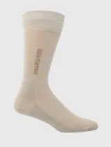 Calcetín formal de largo medio, color beige, con la marca "Hush Puppies" bordada en el lateral de la caña. Presenta un tejido de punto fino y elástico en la parte superior.