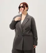 Blazer sastrero oversize color gris, de doble botonadura cruzada, solapas anchas, bolsillos delanteros embutidos y mangas largas.