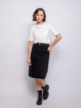 Falda midi de jean color negro, con diseño de cinco bolsillos, cierre frontal con botón metálico y abertura central en el bajo.