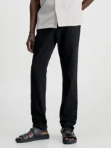 Pantalón chino de sarga elástica, color negro, de corte slim y talle medio. Incluye cinturón con hebilla en forma de D.