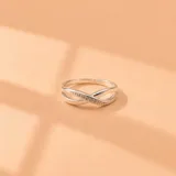 Anillo de plata 925 con diseño entrelazado tipo infinito y engatillado de circonias cúbicas en una de sus bandas.