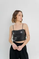 Top crop negro de cuero ecológico con espalda de encaje floral nude, tirantes finos y corte entallado.