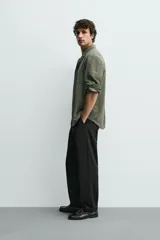Pantalón de corte recto confeccionado en tejido elástico, con cintura elástica, pliegues frontales, bolsillos laterales y bolsillos traseros de vivo con botón.