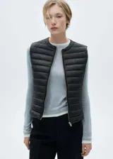 Chaleco acolchado de diseño corto y recto, con cuello redondo y cierre frontal mediante cremallera. Prenda sin mangas con acabado repelente al agua.