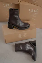 Bota de caña media con punta cuadrada, confeccionada en cuero gamuzado color marrón, con taco bloque y suela de goma negra.
