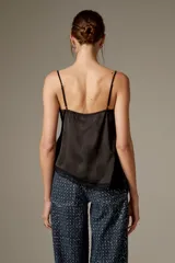 Musculosa de satén color blanco, con breteles finos regulables, escote en V decorado con detalles de encaje y diseño fluido.