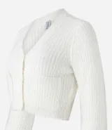 Cardigan cropped de punto color rosa claro, con textura de pelito, cuello en V, mangas largas, cierre frontal con botones y bolsillos delanteros.