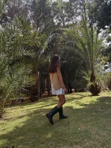 Vestido corto estilo campero, color camel, con tirantes finos trenzados. El ruedo tiene un detalle de volado de tela clara asomando por debajo.