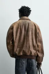 Cazadora relaxed fit de piel con acabado efecto vintage, cuello solapa, manga larga y cierre frontal con cremallera. Presenta bolsillos de plastrón con solapa en la cadera, bolsillo interior y acabados en rib elástico.
