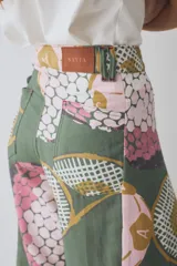 Pantalon de corte wide leg y tiro alto, confeccionado en tela con estampado deportivo que incluye pelotas de futbol y raquetas de tenis en tonos verde, rosa y beige.