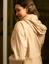 Campera color beige de poliéster, marca Michael Kors. Tiene cierre central oculto con botones a presión, bolsillos delanteros, capucha escondida en el cuello y avíos metálicos dorados con logo.