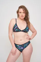 Corpiño de bikini triangular negro con estampado de hojas y flores en tonos turquesa, rosa y verde. Tiene breteles regulables y copas desmontables.