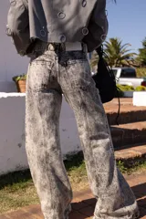 Jean de mujer color gris con efecto acid wash, de tiro alto y corte recto. Presenta costuras verticales en la parte delantera y bolsillos laterales.