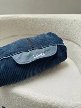 Buzo azul de pana con cierre frontal parcial, cuello alto, bolsillo tipo canguro con solapa y cordón ajustable en el ruedo.