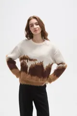 Sweater de punto con diseño de bloques de color en tonos crema, marrón oscuro y caramelo. Presenta una textura afelpada, cuello redondo a la base, mangas largas y corte holgado.