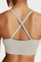 Top deportivo gris con breteles finos cruzados en la espalda, confeccionado en tejido funcional DryMove™ que ayuda a absorber el sudor. Tiene copas forradas con relleno extraíble y elástico ancho en el bajo.