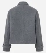 Saco corto de corte regular confeccionado en polivelour gris, con cuello inglés, cierre frontal de doble abotonadura con botones dorados y mangas largas con detalle de trabas en los puños.