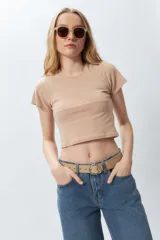 Top corto color beige, ajustado al cuerpo, de manga corta y cuello redondo.