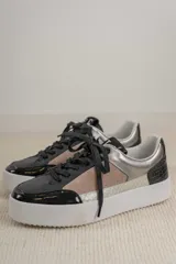 Championes urbanos con diseño de paneles en tonos verde oliva, negro y gris. Presentan una combinación de texturas que incluye cuero liso, gamuza y un panel con estampado de piel de serpiente en el talón. Cuentan con cordones negros y una suela de plataforma blanca con textura acanalada.
