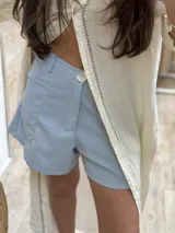 Short de lino en color celeste, con diseño de tiro alto, cierre frontal con botón a la vista y costuras decorativas verticales en el frente.