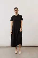 Vestido midi negro con diseño de manga corta, cuello redondo y bolsillos laterales, corte amplio y fluido.