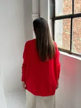 Sweater de punto color rojo, con cuello redondo, mangas largas con puños acanalados y diseño holgado con detalle de costura vertical central.