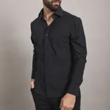 Camisa de vestir negra de manga larga, confeccionada en tejido técnico elástico y libre de arrugas, con cuello clásico y cierre frontal de botones.