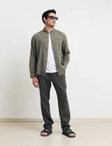 Camisa de cuello mao y manga larga, confeccionada en una mezcla de lino y algodón. Presenta un diseño de corte recto con botones en tono natural y un bolsillo pequeño en el pecho.