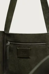 Bolso tipo shopper de cuero con acabado en serraje, color verde oscuro. Cuenta con un compartimento principal amplio, un bolsillo interior con cierre de cremallera y dos asas de mano.