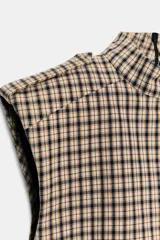 Mono corto de cuello subido y manga sisa con hombreras, con diseño de cuadros tipo tartán en tonos beige y negro. Cuenta con trabillas en los hombros y cierre en la espalda con cremallera oculta.