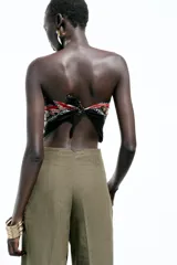 Pantalón de lino negro, de tiro alto, con bolsillos delanteros de vivo, pernera recta y cierre frontal con cremallera, botón interior y gancho metálico.