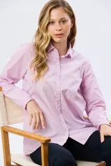 Camisa de manga larga de corte holgado, con diseño de rayas rosadas y blancas, cuello camisero y cierre frontal de botones.
