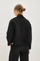 Tapado corto de paño en color tostado, con diseño de doble abotonadura, cuello solapa y mangas largas.