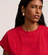 Blusa roja de corte slim, con cuello redondo, mangas cortas y detalle de bordado de follaje al tono en el frente.