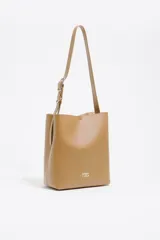 Bolso de hombro Bimba y Lola modelo Carlino, de estructura rígida y tamaño mediano, confeccionado en piel vacuna color tostado. Presenta asa regulable de piel con hebilla metálica y logo impreso en la parte inferior.