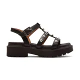 Sandalia negra con plataforma, tiras con apliques metálicos y hebilla lateral.