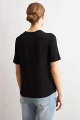 Remera negra de manga corta con panel frontal de tela broderie con diseño geométrico de rombos y espalda lisa.