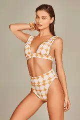 Bikini de dos piezas con estampado de lunares grandes en color naranja quemado y blanco. El corpiño es de escote profundo en V con tirantes anchos. La bombacha es de tiro alto.