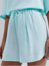 Short de cintura alta con elástico y cordón ajustable, confeccionado en tela ligera con textura, de corte holgado y ruedo redondeado.