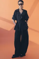 Pantalón de tiro medio con diseño wide leg, confeccionado en mezcla de lyocell. Presenta pinzas en el delantero y cierre frontal con cremallera, botón y ganchos metálicos.