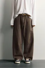 Pantalón barrel fit de mezclilla color verde militar, con efecto lavado, cinco bolsillos, cierre frontal con cremallera y botón, y detalle de pinzas en las rodillas.