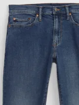 Jean de corte slim taper en color azul índigo medio, con diseño de cinco bolsillos, cierre de botón y cremallera.